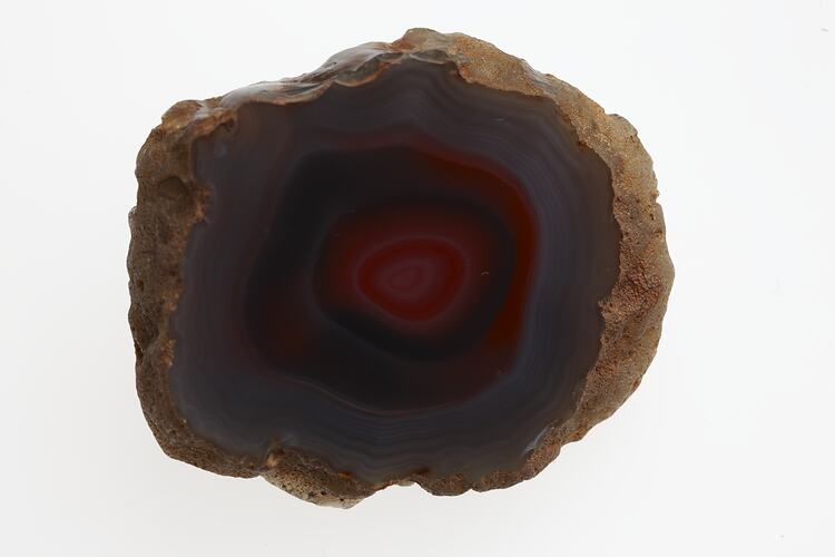 Agate cross section with red centre and dark blue surround.
