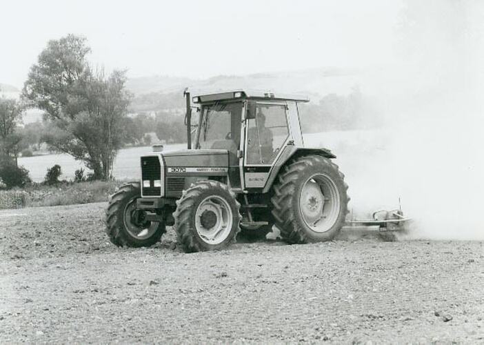 Man driving a tractor with scarifier in field.