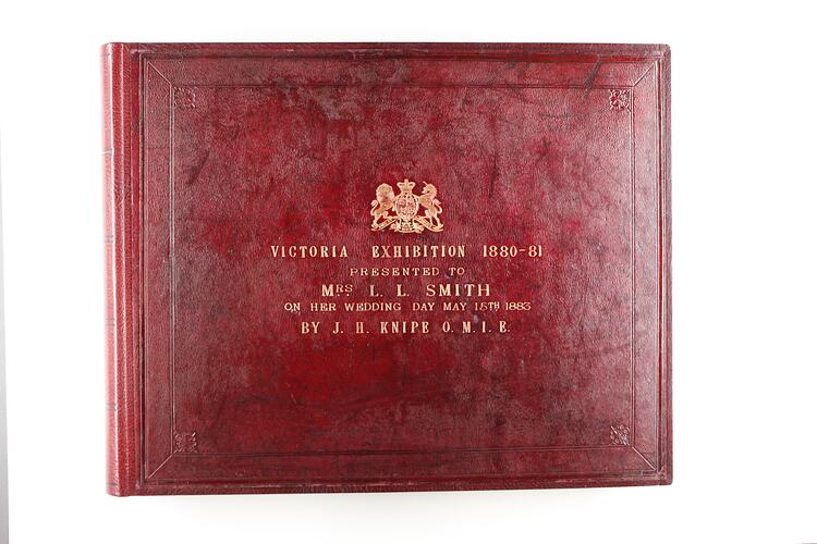 Red leather covered photograph album with decorative gold tooled border and gold tooled lettering in centre.