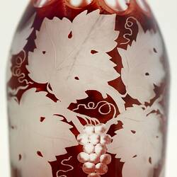 Glass decanter with a red grape vine pattern.