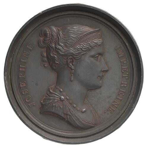 Round dull bronze medal with female facing right. Text around.