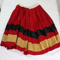Back of red gathered skirt, wide silk black and cream (discoloured) stripe. Narrow white waistband.