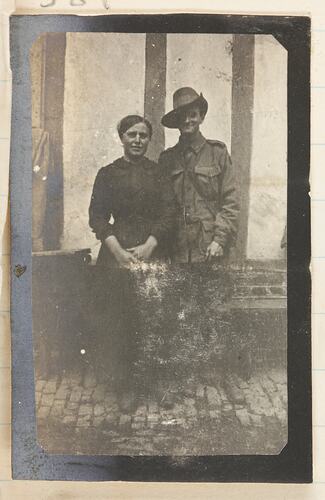 Woman and soldier standing side by side in front of a building.