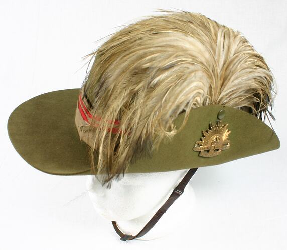 Side view of khaki hat with feather.