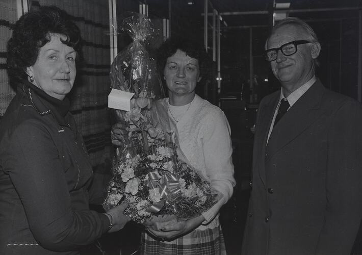 Three people, one holding a basket of flowers.