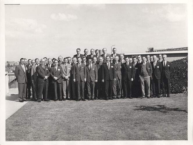 Group portrait of men in suits on lawn.
