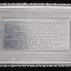 Decorative silver snuff box with engraved text.