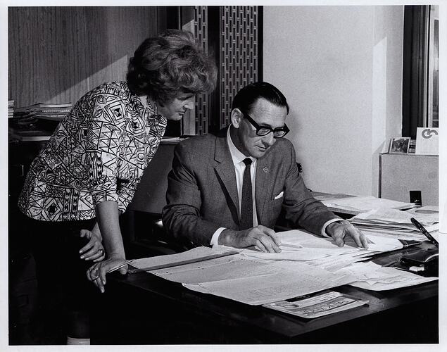 Man and woman reviewing papers on office desk.