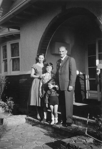 Family of four on front steps of house.