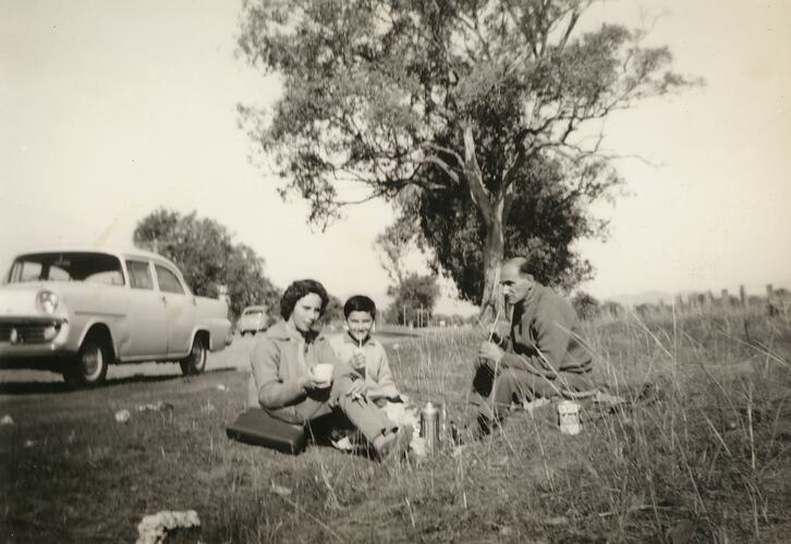 Man, woman and child sitting at roadside.