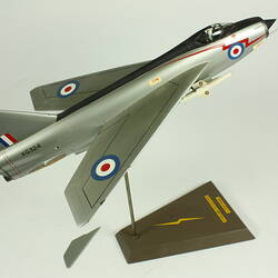 Silver model aeroplane. Blue, white and red rondels on wings and fuselage. On stand.