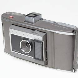 Camera, taupe and metal. Front left quarter view.