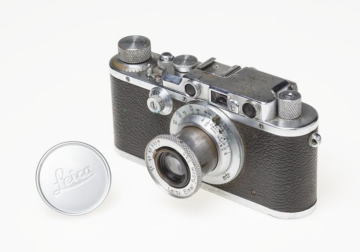 Black leather and silver metal bodied camera. Silver lens at front and dials, buttons on top.