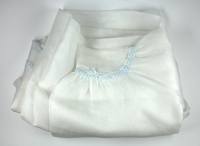 Piece of sheer white fabric with blue trim showing curved hem.