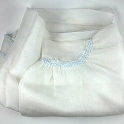 Piece of sheer white fabric with blue trim showing curved hem.