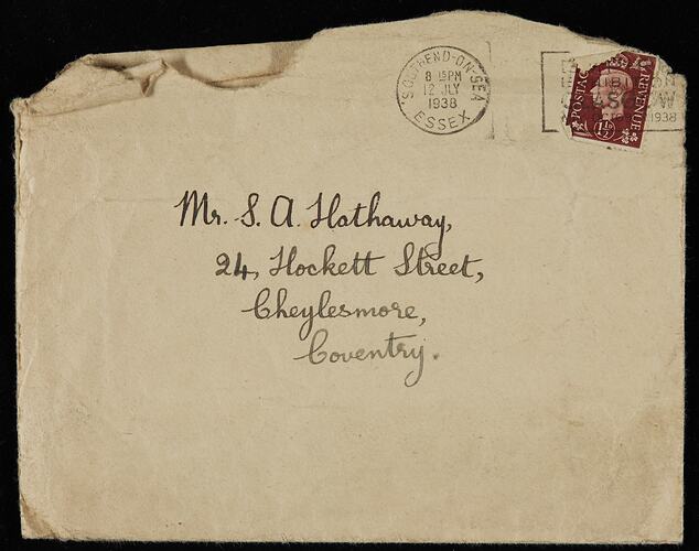 Cream envelope, opened, with handwritten text in black ink. Black ink stamp, red postage stamp at top right.