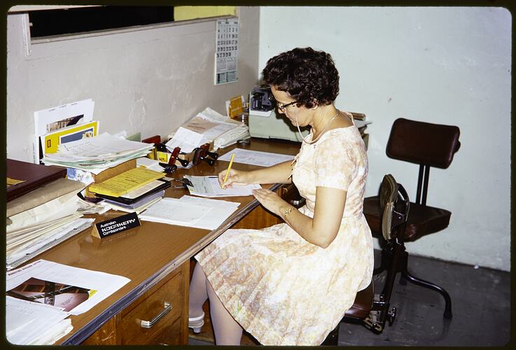 Woman seated a desk.