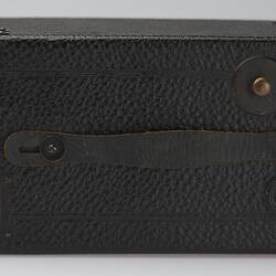 Black box shaped camera. Attached leather flat handle.