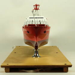 Container ship with red hull facing front.