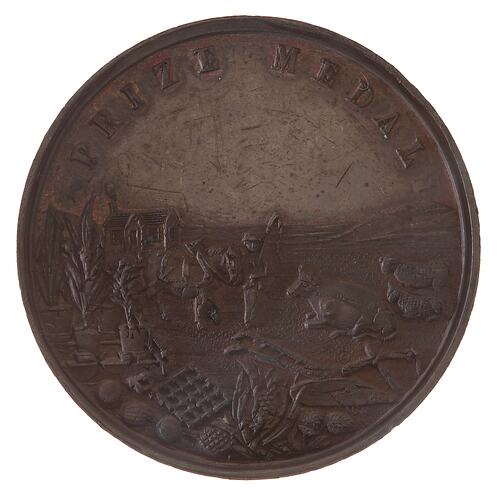 Round brown medal with rural scene of a farm house, farmer and farm animals.