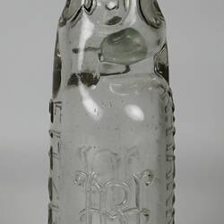 Clear glass bottle with raised inscription.