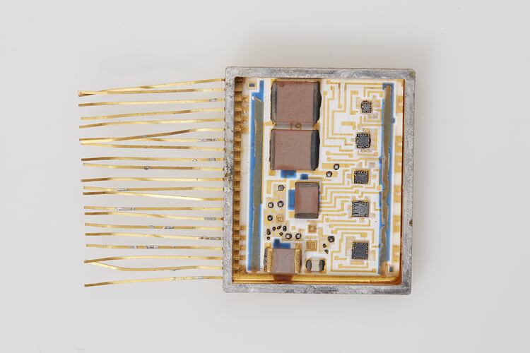 White microchip with thin gold strands attached along left side.