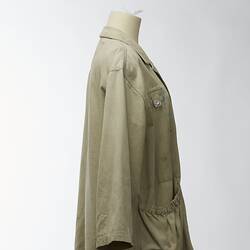 Large beige coat with elasticised pockets. Right side view.