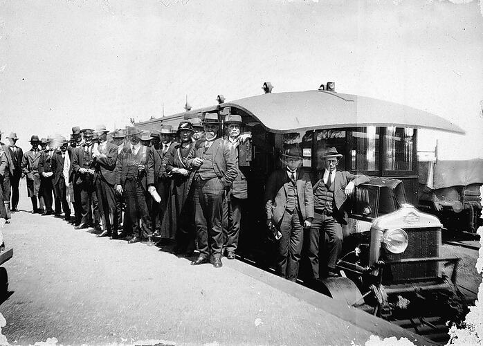 Men standing beside the motor rail, Sea Lake Station, circa 1920.