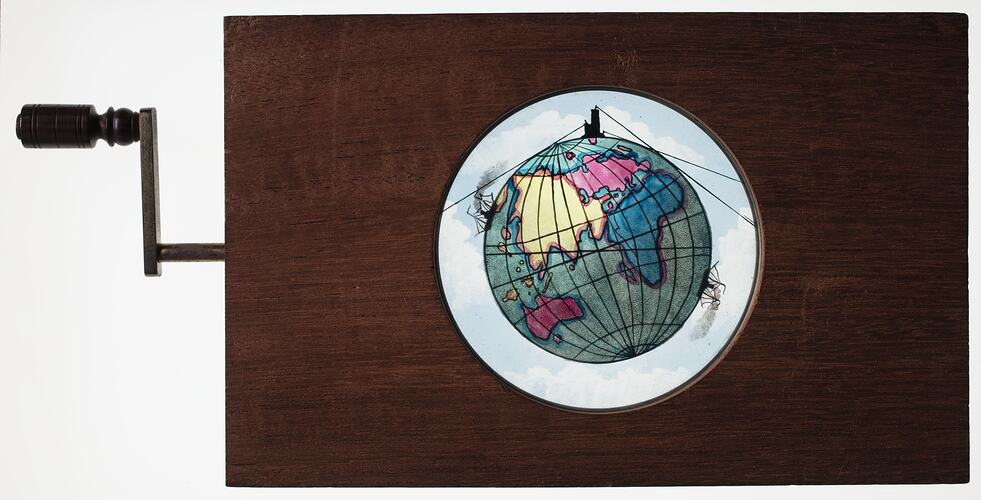 Wooden slide with handle on left side. Central round glass slide with coloured illustration of Earth.