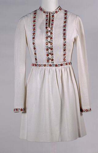 Long sleeve cream wool mini dress. Decorative braid on bodice, around neck, cuffs, waist.