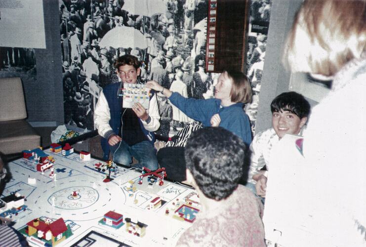 A group of children building on Lego machines around a low table.