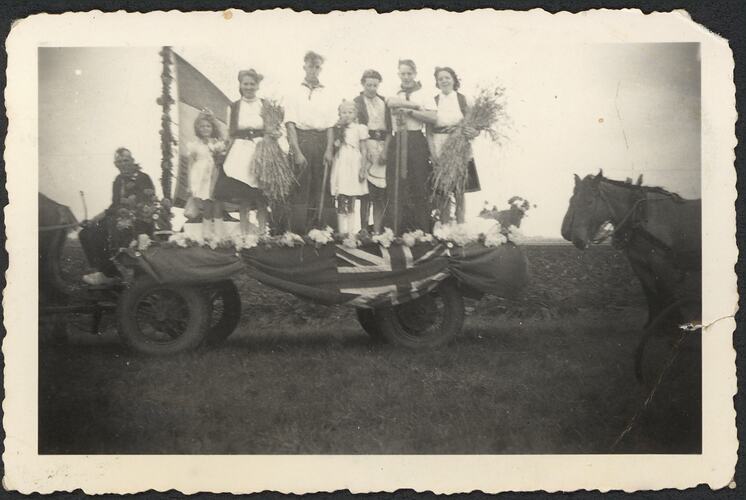 Liberation Day float with group in costume standing atop. Horse at right.