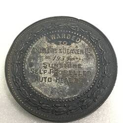 Reverse of circular silver medal. Wreath framing embossed inscription.