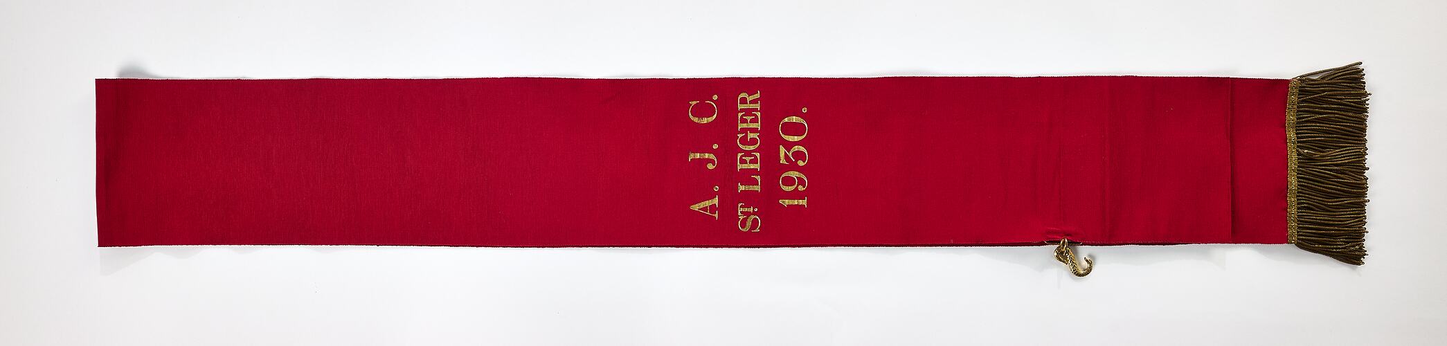 Red ribbon sash with gold lettering and fringe.