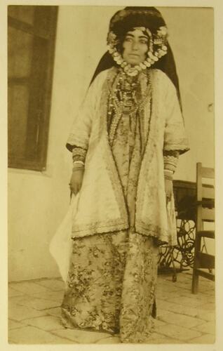 Kurdish woman wearing gold jewels and robes.