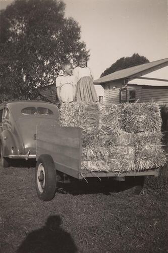 Digital Photograph - Boy & Girl Standing on Hay Bales Loaded on Trailer, Springvale, 1950s