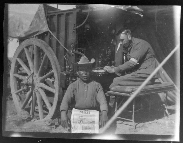 Two uniformed men next to cart with communications equipment.