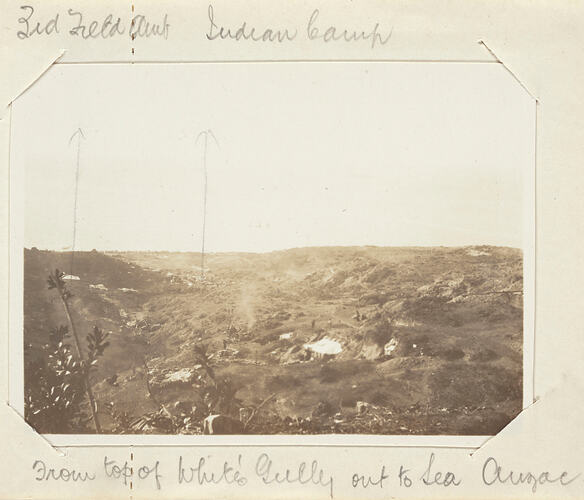 Hilly scrub covered landscape with servicemen scattered around.