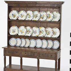 Model of wooden dresser and top with floral plates.