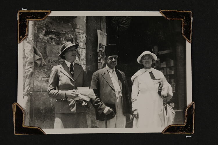 Two women and a man standing in front of building.