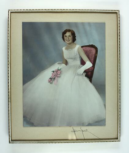 Framed photo of seated woman in white dress with tulle skirt.