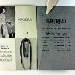 Open grey-covered booklet with photo of woman and vacuum cleaner