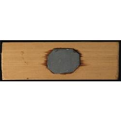 Underside of wooden microslide with central metal plate.