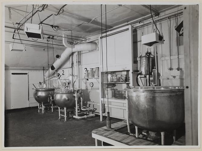 Industrial interior, dominated by three large round vats.