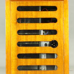 End view of wooden box with open slats partially showing internal electrical components.