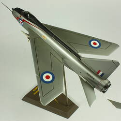 Silver model aeroplane. Blue, white and red rondels on wings and fuselage. On stand.