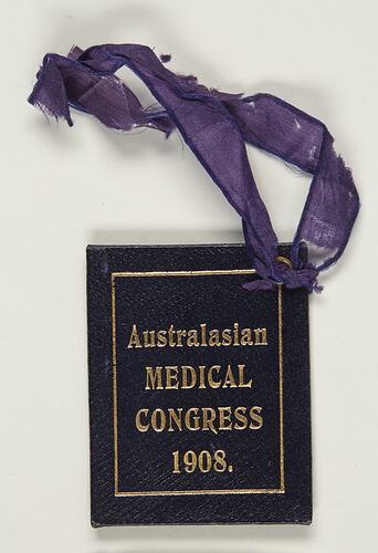 Dark blue textured card with gold text. Attached to a frayed purple ribbon.