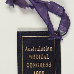 Dark blue textured card with gold text. Attached to a frayed purple ribbon.