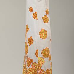 Left side long sleeveless white cotton dress. Orange and yellow floral printed pattern.