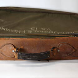 View of leather handle of khaki canvas valise (bag) with inscriptions.